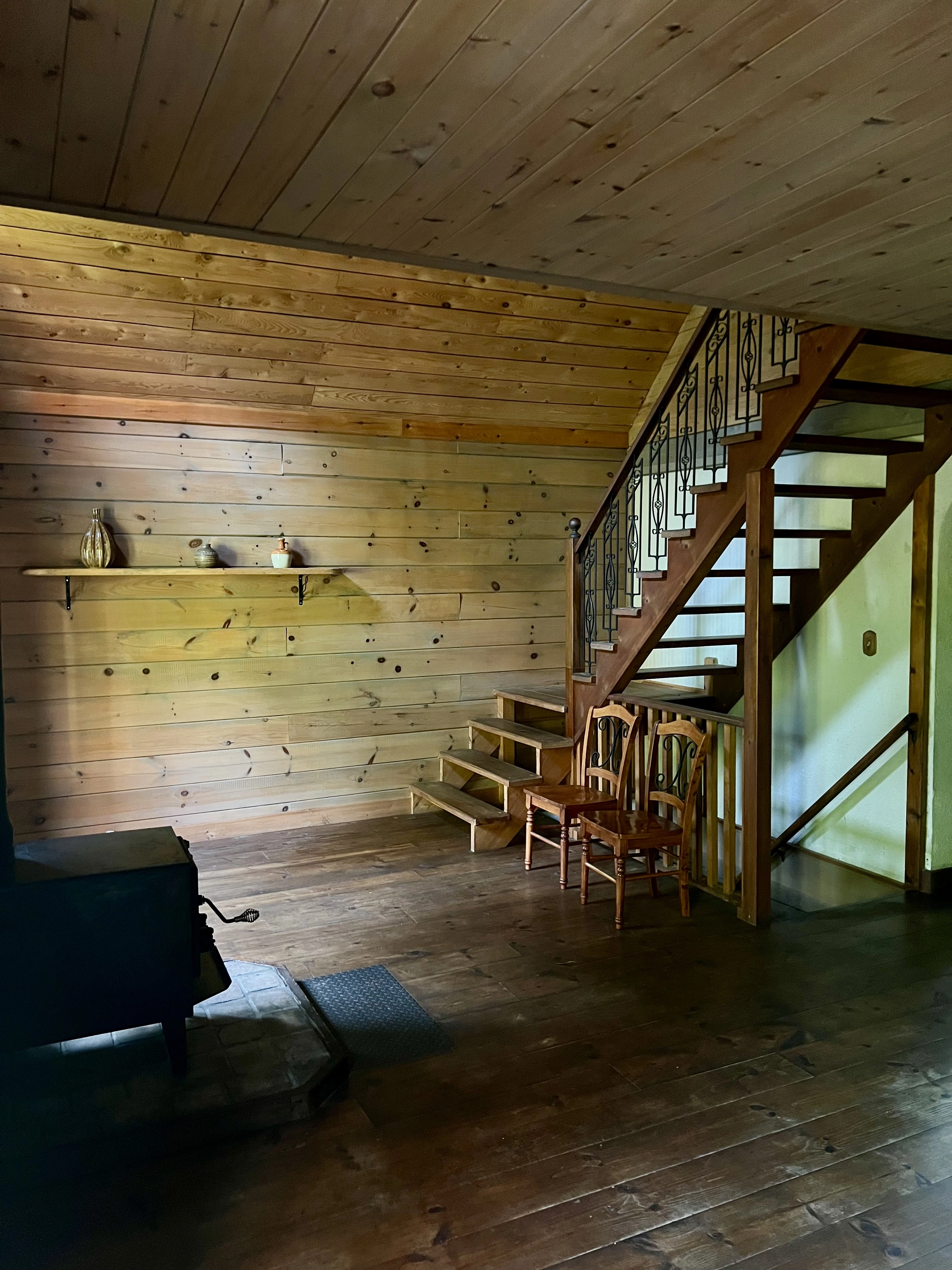 Espace de vie avec poêle à bois et escalier