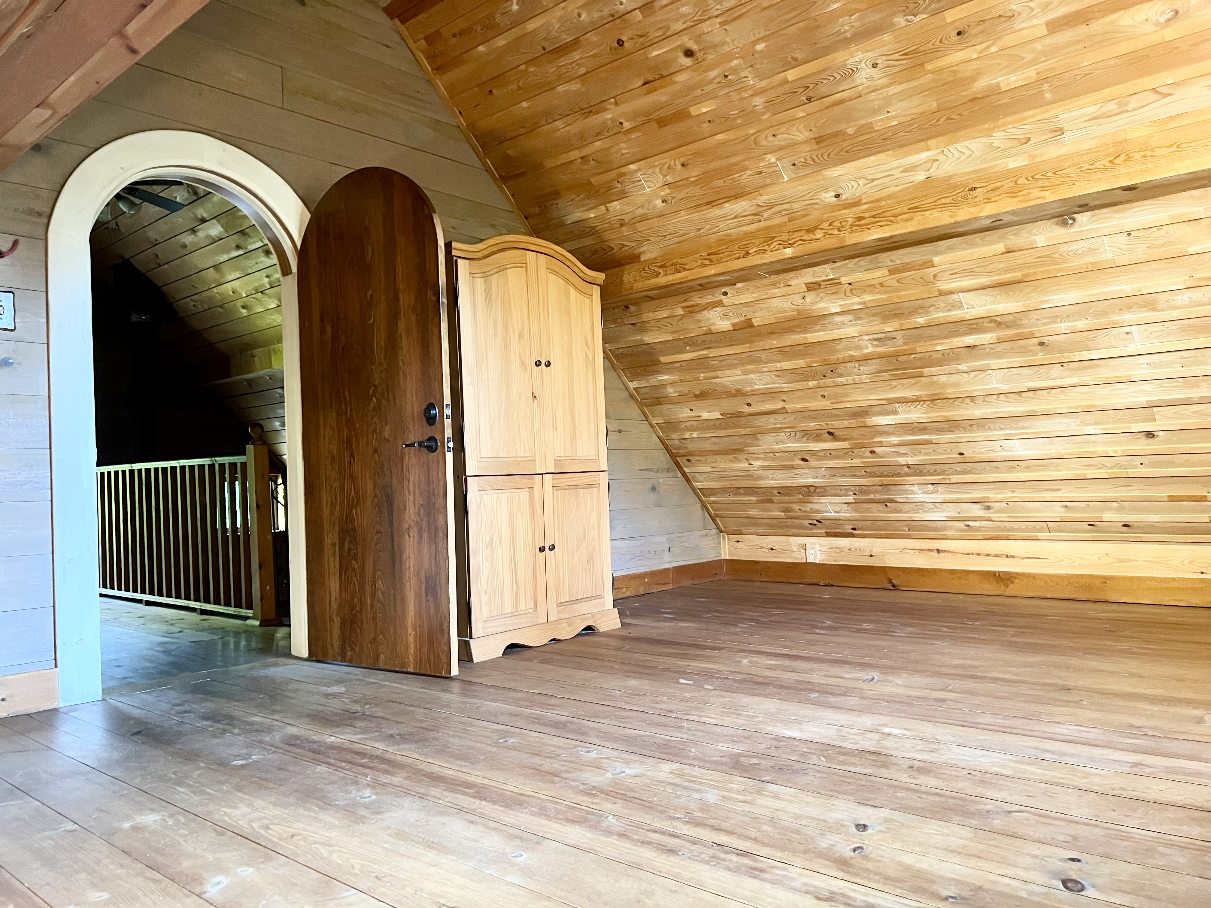 Loft bedroom with wood ceiling and arched door
